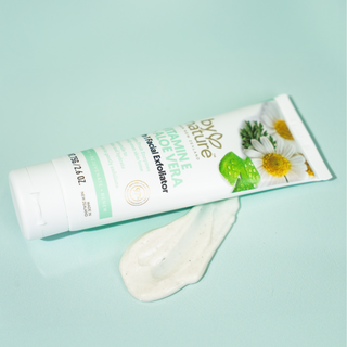 Tube of By Nature Vitamin E + Aloe Vera Exfoliator and swatch on a light green background