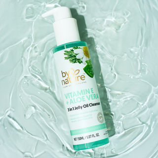 Bottle of 'by Nature' Vitamin E + Aloe Vera 3-in-1 Jelly Oil Cleanser on a textured light green background