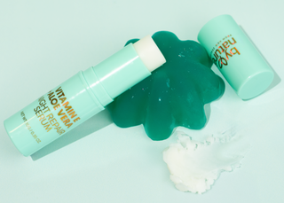 By Nature Aloe Vera and Vitamin E serum stick leaning on jelly, next to a swatch of serum on a light blue background