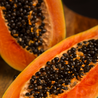 Close-up of a halved papaya with seeds on a wooden background