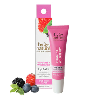A pink and white tube of By Nature Vitamin E + Wild Berry Lip Balm stands next to its matching retail box, with fresh berries and mint leaves at the base, on a plain white background.