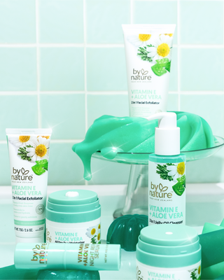 Collection of 'by nature' skincare products on a light blue tiled with green jelly and plain background